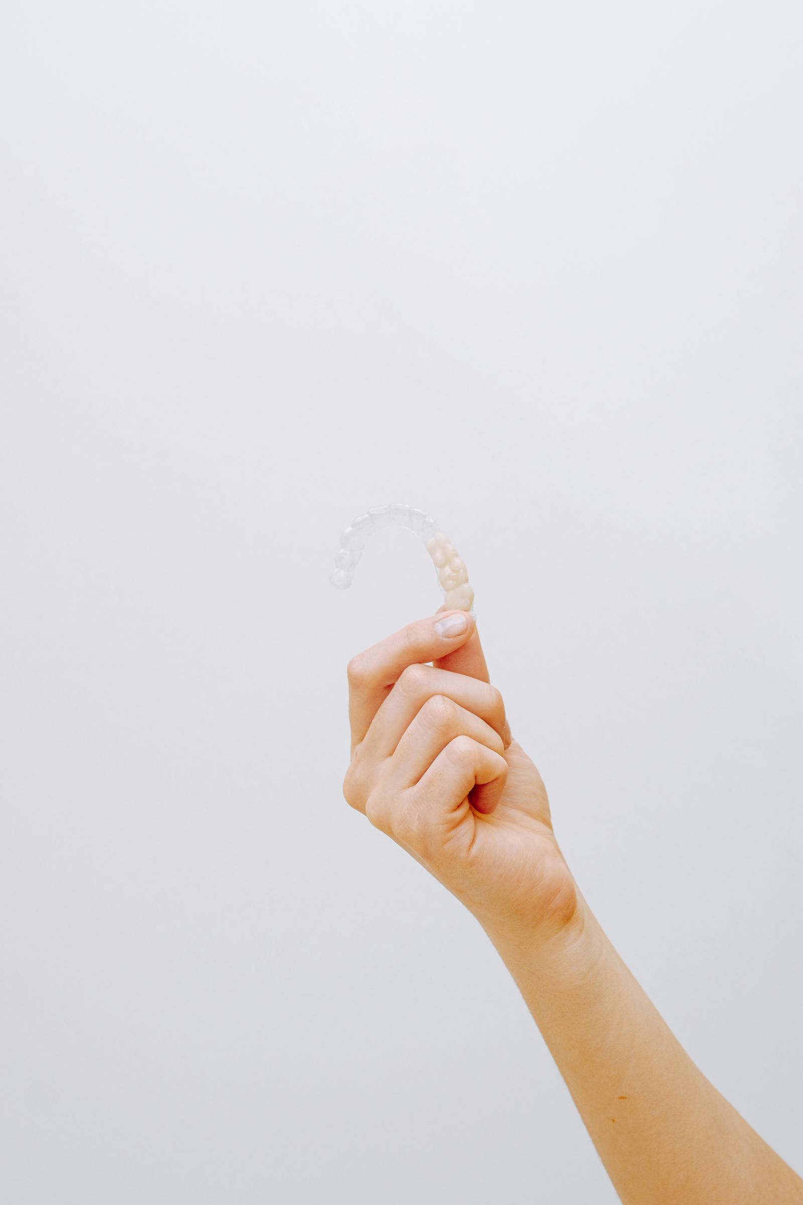 Hand hält eine transparente, herausnehmbare Zahnschiene